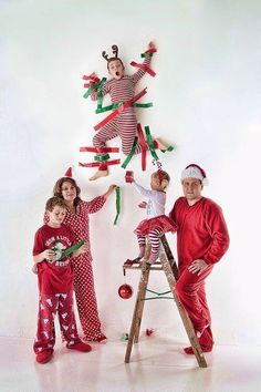 two adults and three children in christmas pajamas standing next to a ladder with decorations on it