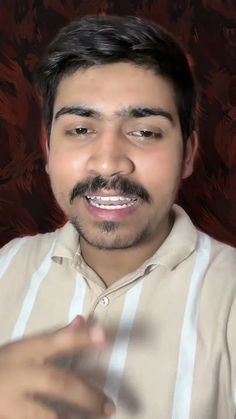 a man with a mustache is making a face while holding his hand out to the camera