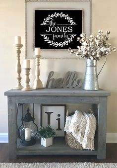 a shelf with flowers, candles and pictures on it in front of a wall hanging