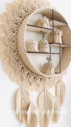 a white wall hanging with some tassels and other items on the shelf in front of it