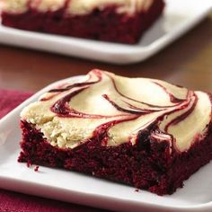 a piece of red velvet cake with white frosting on a square plate next to a fork