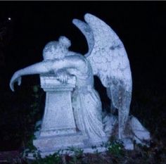 an angel statue in the dark with its wings spread