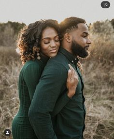 a man and woman embracing each other in an open field