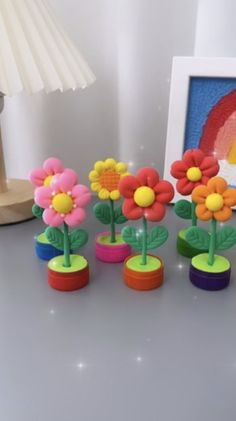 a group of small plastic flowers sitting on top of a table next to a lamp