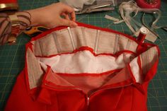 someone is working on something that looks like a red shirt with white piping and zippers