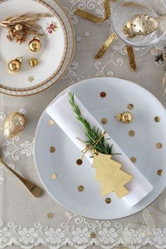 a white plate topped with a gold christmas tree ornament next to other plates