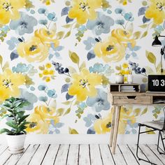 a wall with yellow and blue flowers on it next to a wooden table in front of a white wall