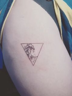 a woman's shoulder with a small wave and triangle tattoo on her left arm