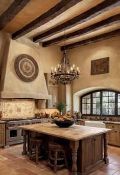 a large kitchen with an island and chandelier in the center, surrounded by wooden beams