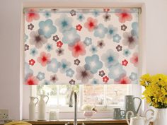 a kitchen window with flowers on the roman blind in red, white and blue colors