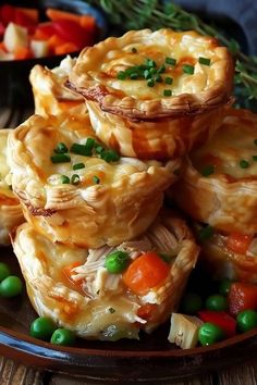 several small pies on a plate with peas and carrots next to some other food