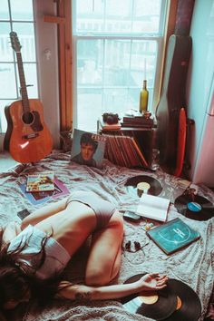 a woman laying on top of a bed next to a guitar