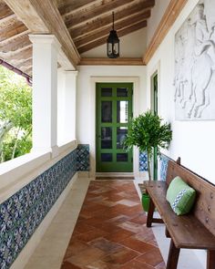 a wooden bench sitting on top of a tiled floor next to a green front door