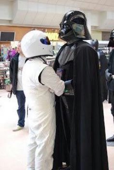 two people dressed as darth vader and stormtrooper are standing in a mall