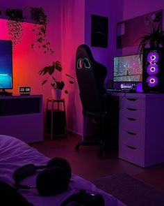 a room with a bed, computer desk and headphones on top of it in front of a purple light