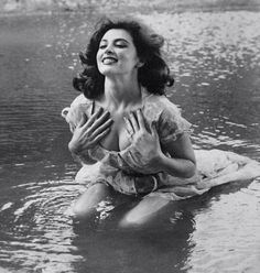 an old photo of a woman sitting in the water with her hands clasped up to her chest