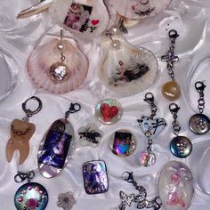 many different types of charms on a white cloth with shells and seashells around them