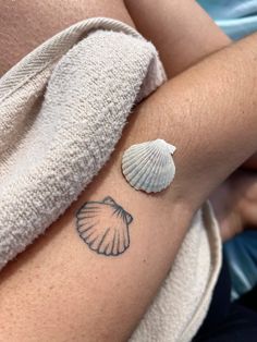 a woman with a tattoo on her arm has a seashell tattooed on her left side