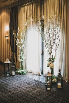 two tall vases with flowers and greenery on the floor