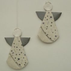 two white and gray ornaments hanging from strings on the wall, one with an angel's wing