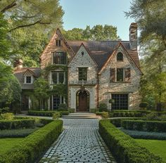 a large brick house surrounded by trees and bushes with a stone walkway leading to the front door