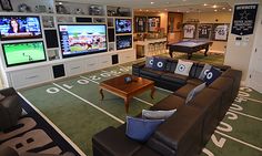 a living room filled with lots of furniture and flat screen tvs on the wall