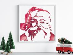 a red and white painting with santa claus on it next to christmas trees in the foreground