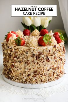 a cake topped with strawberries and nuts on top of a white table next to tulips