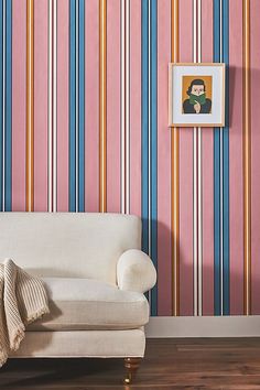 a white couch sitting in front of a wall with colorful stripes on it's walls