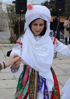 two women dressed in traditional clothing dancing on the street