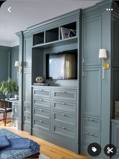 an entertainment center in a living room with blue walls and wood floors, built - in cabinets