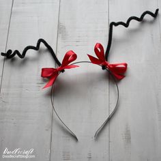 a mickey mouse ears headband with red bows on top of it, sitting on a white wood floor