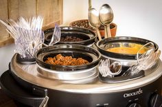 the crock pot is full of different types of food and spoons on top of it