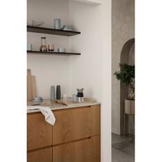 a kitchen with wooden cabinets and shelves filled with dishes on top of each shelf, next to a potted plant