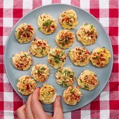 a plate full of small appetizers on a red and white checkered table cloth