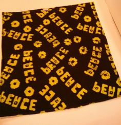 a black and yellow scarf with letters on it sitting on top of a white table