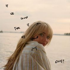 a woman standing next to the ocean with writing on her face and words above her head