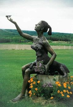 a statue of a woman sitting on top of a tree stump holding a bird in her hand