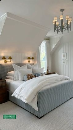 a large bed sitting under a window next to a chandelier in a bedroom