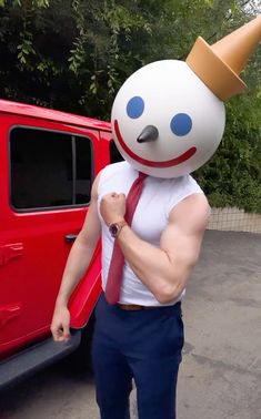 a man wearing a red tie and white shirt standing next to a red truck with an inflatable character on it's head