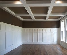 an empty room with white paneling and wood floors