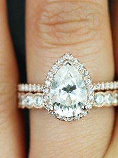 an engagement ring with a pear shaped diamond in the center and side stones on each band