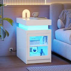 a white night stand with blue lights on it in front of a couch and coffee table