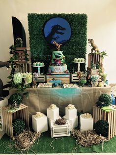 a table topped with cakes and desserts covered in greenery next to a wall