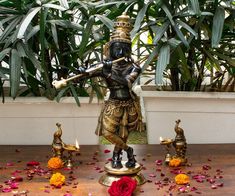 a statue is surrounded by flowers and candles in front of a potted palm tree