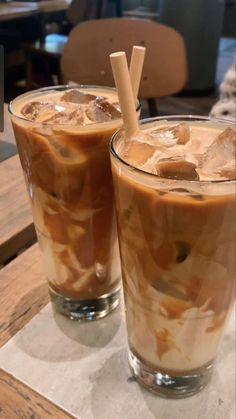 two glasses filled with iced coffee sitting on top of a table