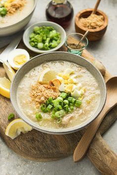 there is a bowl of soup on the table with lemons and other ingredients around it