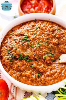 a white bowl filled with red sauce and garnished with parsley