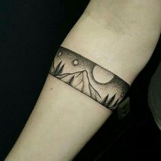 a black and white tattoo on the arm of a person with mountains in the background