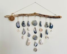 a wall hanging with different types of rocks and chains on it's side, along with a wooden stick